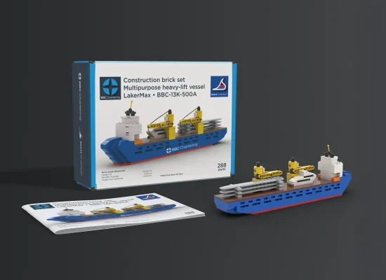 Ein Klemmbausteinmodell eines blauen und grauen Mehrzweck-Schwergutschiffs mit gelben Kränen wird mit der Schachtel und der Bauanleitung auf einer dunklen Fläche ausgestellt. Die Schachtel trägt die Aufschrift LakerMax - BBC-13K-5000A und enthält 288 Teile.