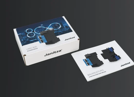 Ein Klemmbausteinmodell eines Janitza UMG 800 Gerätes wird neben der Produktverpackung und der Bedienungsanleitung auf einer dunklen Fläche gezeigt. Auf dem Karton sind ein Stadtbild und das UMG 800-Label abgebildet.